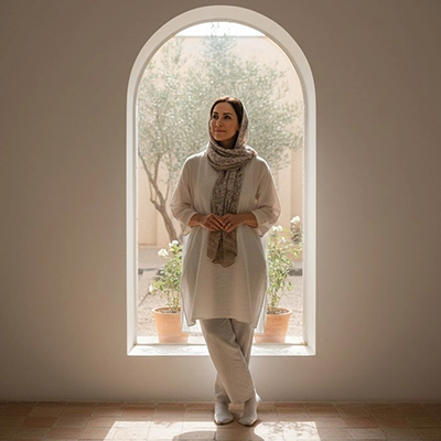 زن جوان با لاس روشن ایستاده مقابل پنجره بزرگ